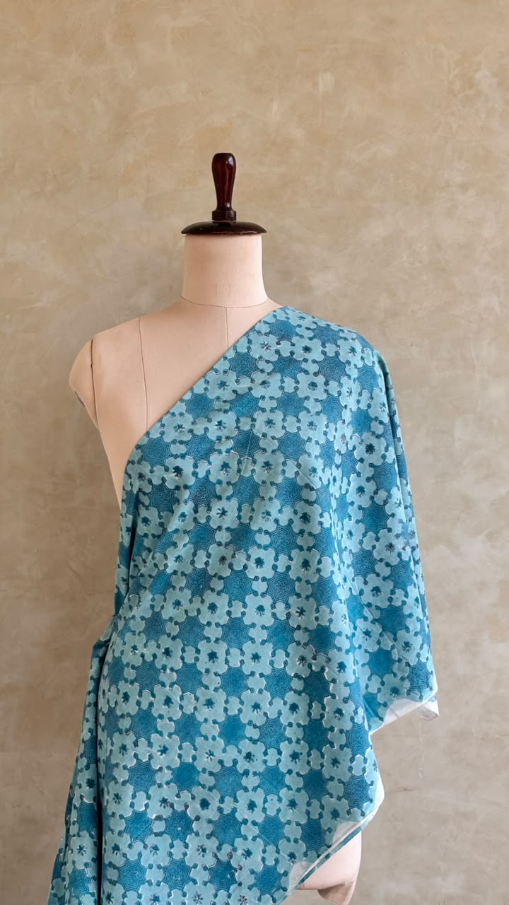 Teal blue fabric featuring a floral block print design.