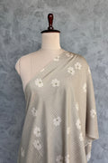 Beige muslin fabric with white daisy floral prints and subtle self-stripes.