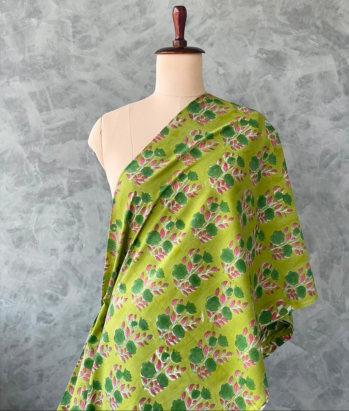 Fresh green Jaipur cotton fabric featuring pink floral prints.