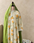 A cream-colored tunic dress with a yellow and green floral print, displayed on a mannequin with a matching green dupatta draped over the shoulders, set against a textured beige wall.