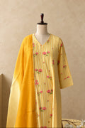 A yellow and gold printed kurta with pink floral embroidery, displayed on a mannequin with a matching yellow dupatta against a textured gray wall.